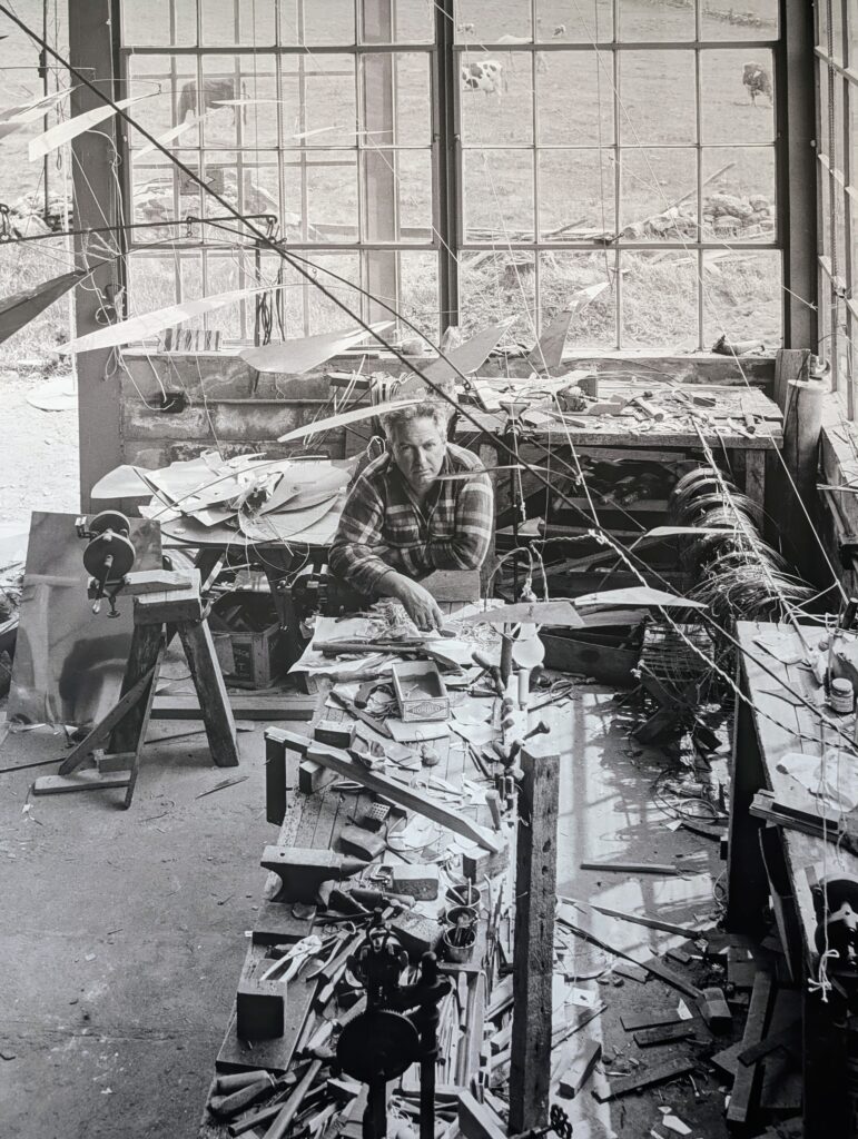 Portrait d'Alexander Calder dans son atelier entouré de mobiles