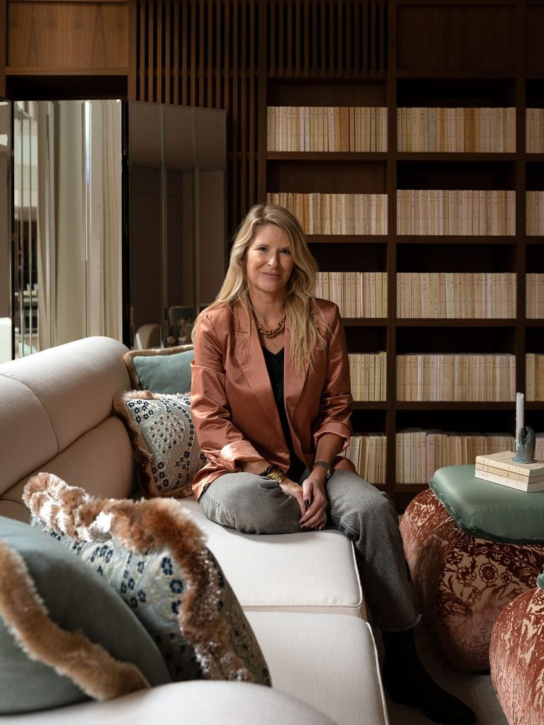 Dorothée Delaye, architecte d'intérieur, assise sur un canapé blanc devant une bibliothèque